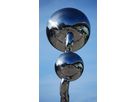 Two polished stainless steel spheres arranged vertically with connecting element against a blue sky