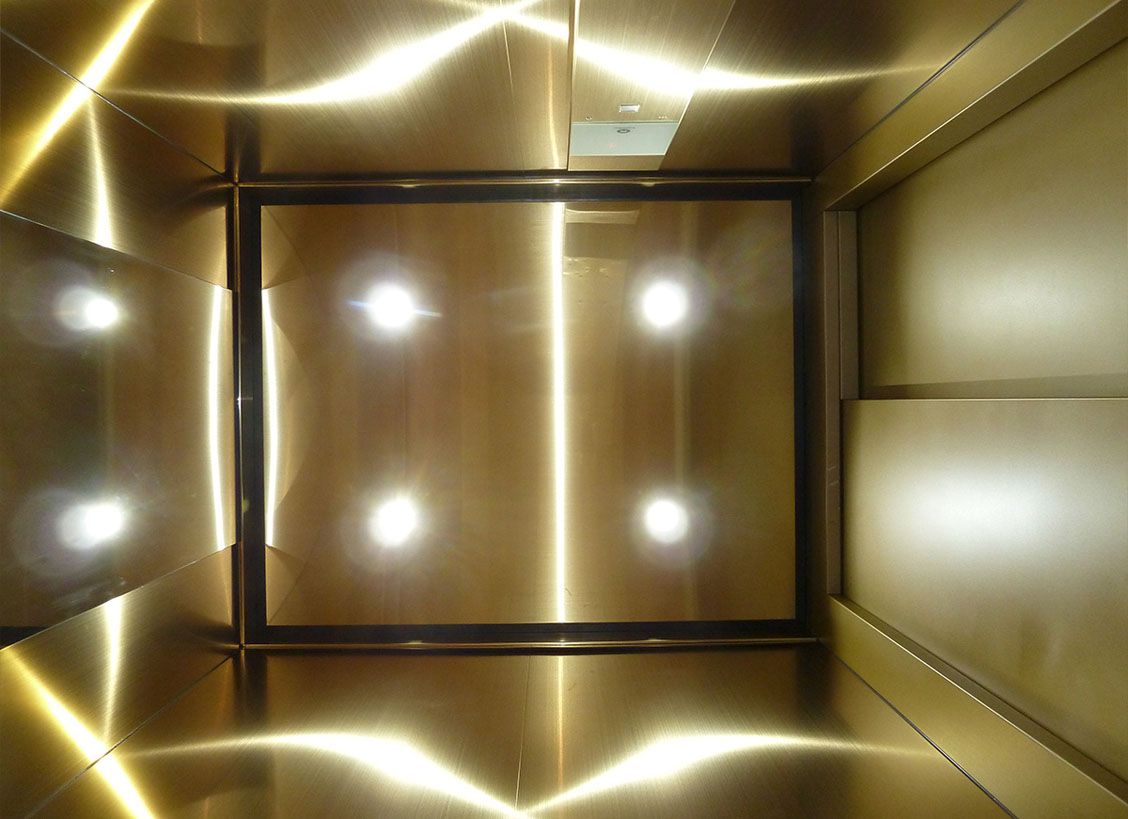 Vue du plafond d’une cabine d’ascenseur dorée en acier inoxydable Oro HL avec spots intégrés