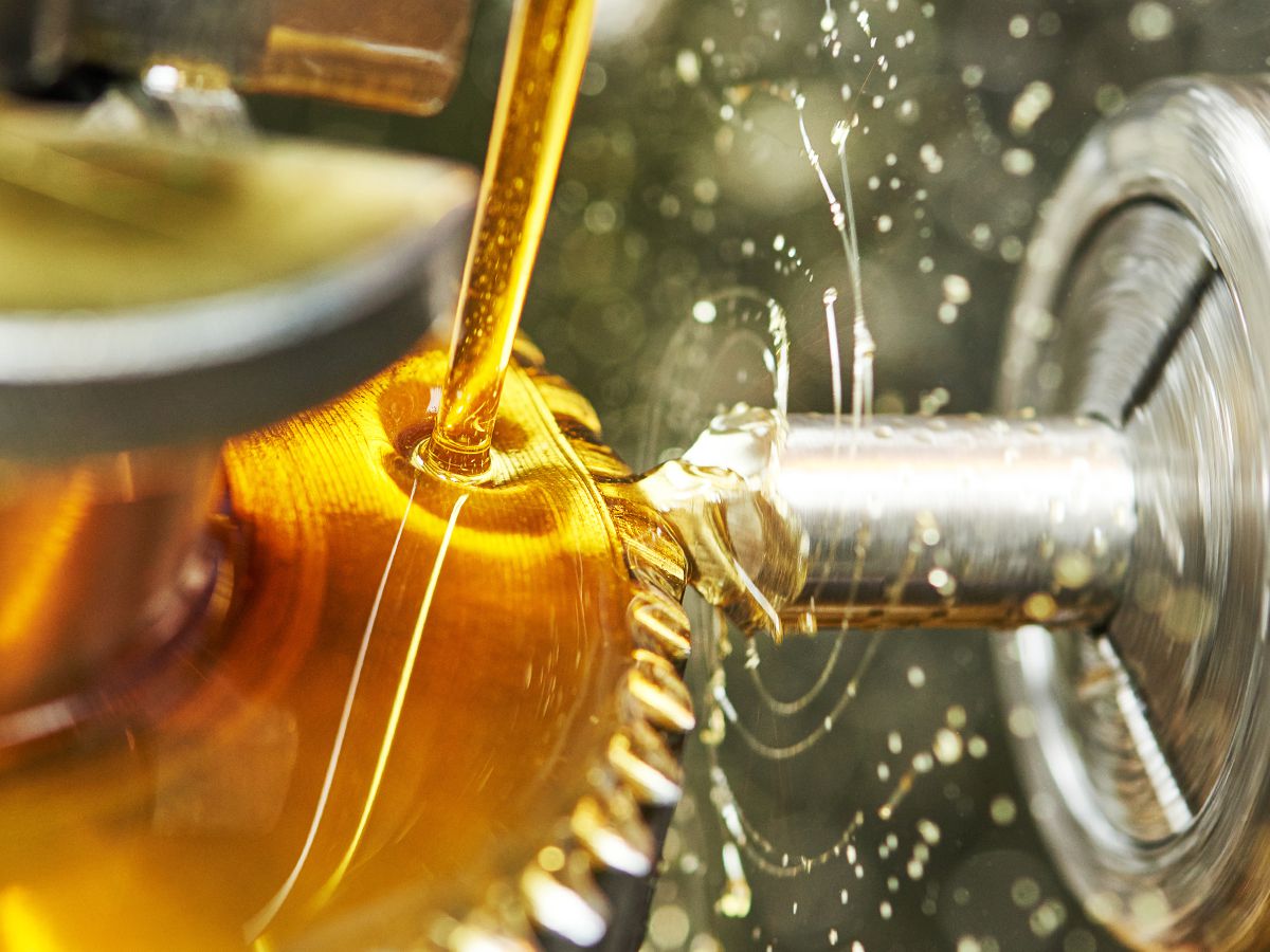 Rotating metal component being machined while lubricant is applied to the workpiece.