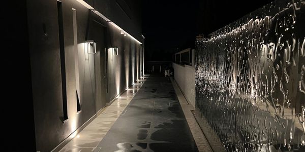 Portail d’entrée avec surface en acier inoxydable structurée en vagues le long d’une allée éclairée de nuit