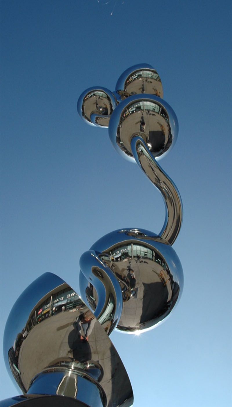 Polished stainless steel spheres with curved tubular connecting element against a blue sky
